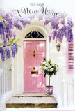 This image captures a tranquil Tring doorway bathed in soft, natural light, the kind you might notice while strolling back from Tring Park on a calm afternoon. Above the entrance, sweeping strands of lavender wisteria fall in delicate, fragrant curtains, their blossoms clustered and abundant, creating a dreamy archway that frames a pale pink front door. The door's colour is a gentle, comforting blush, set against whitewashed walls that reflect the sun and make the whole frontage glow. To one side, a lightly painted shutter adds to the cottage-like charm, holding the light in such a way that subtle shadows drift across the façade, giving the scene depth and quiet movement. On the doorstep sits a modest yet beautifully styled tin bucket, transformed into a statement piece by the flowers it holds. It is generously filled with white and cream roses, each bloom full and rounded, with soft, velvety petals unfolding over one another. Between the roses, touches of soft green foliage provide a fresh contrast, suggesting the bouquet has been arranged recently and with a careful eye. Around the bucket, a pastel pink ribbon is tied in a neat bow, echoing the hue of the front door and creating a harmonious, pastel palette. The overall mood is one of gentle optimism and affection, perfectly suited to a housewarming gift for a new address near Tring's High Street or along Akeman Street. You can almost sense the subtle fragrance drifting on the air, welcoming anyone who steps close with an unspoken message of comfort, hope, and the joyful start of a new chapter at home.