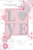 In this image, the anniversary card presents itself like a soft whisper of affection, its design rich in gentle detail yet never overpowering, much like a thoughtfully chosen bouquet delivered to a doorstep in Tring. The centre of the card holds the word LOVE, each letter raised and coated in fine, pale glitter that glows softly rather than sparkling harshly. The letterforms sit on a blush-pink panel, with a subtle gradient that makes the centre appear softly lit, as if illuminated by afternoon light filtering through a window on Akeman Street. Around this central word, the floral illustration unfolds in graceful arcs: delicate blossoms in blush, mauve, and pearl white seem to unfurl from slender stems, while silvery leaves and scrolling vines weave between them. The flowers have a slightly stylised look, their petals outlined in fine lines and shaded with a watercolour softness, like the preliminary sketch a florist might make before arranging real stems into an anniversary display. Tiny details-petals drifting loose, gentle curls of foliage, almost-hidden butterflies-add a feeling of movement, as though a light breeze is playing across the card. The text, including phrases such as On Our Anniversary and a tender declaration of ongoing love, is written in graceful, understated script that flows naturally with the curves of the design. Muted greys and silvers balance the pink tones, lending sophistication and calm. Altogether, the card feels like a keepsake that captures the hush of shared moments and long-lasting devotion, echoing the romantic spirit of anniversary flowers sent across Tring.